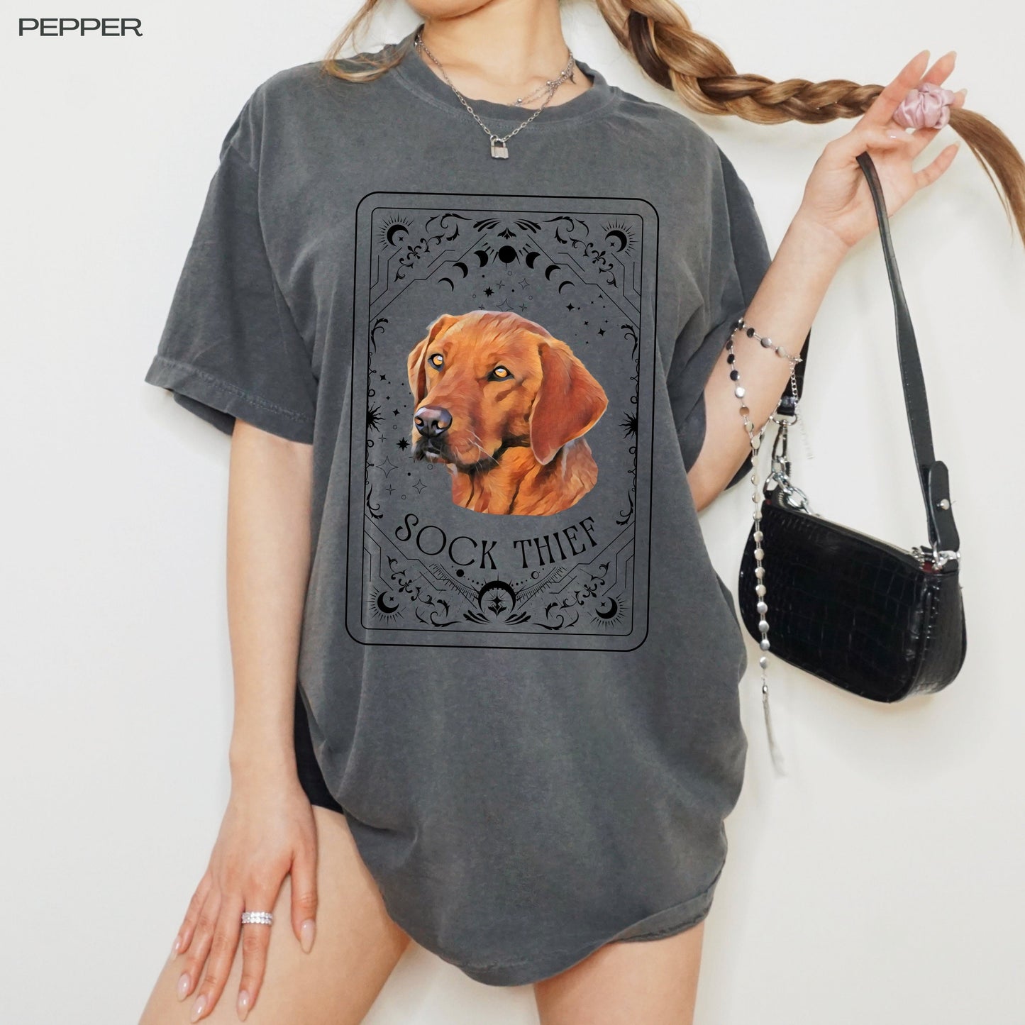 A woman wearing a tarot inspired red fox Labrador retriever dog shirt and holding her braid in one hand