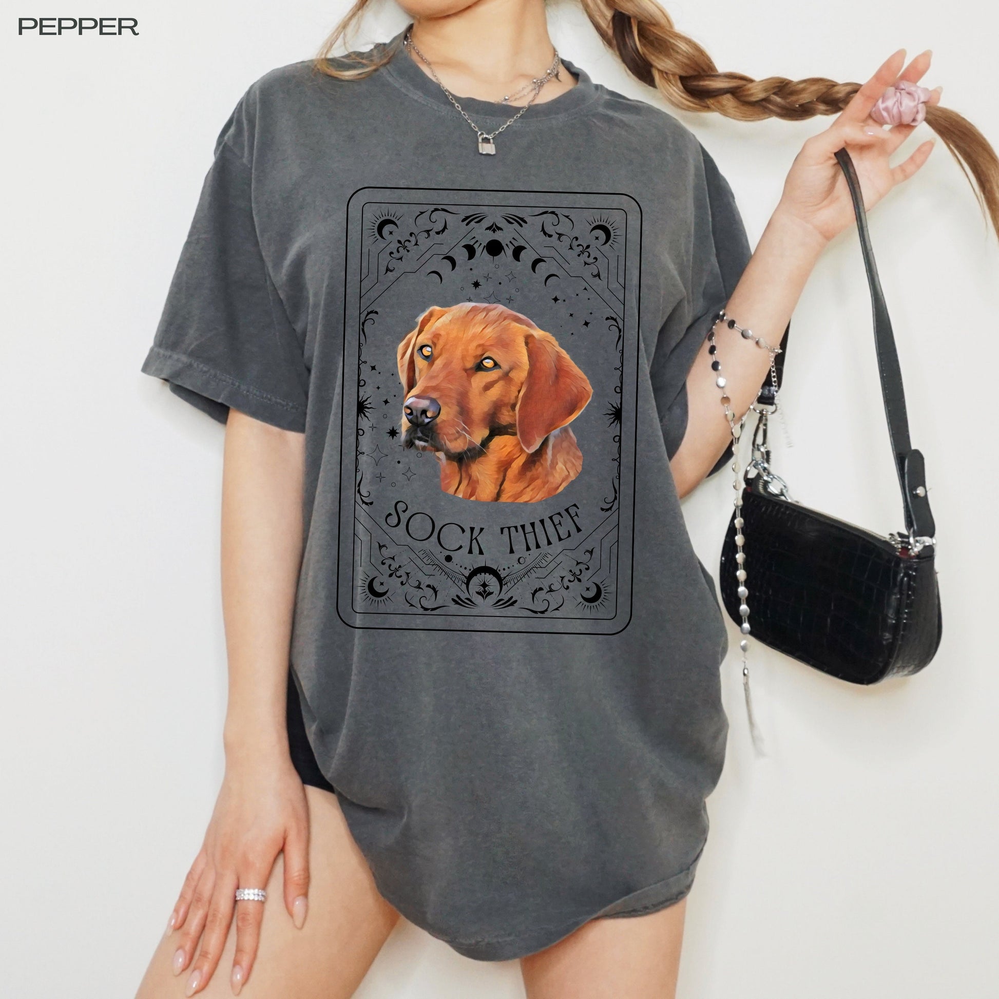 A woman wearing a tarot inspired red fox Labrador retriever dog shirt and holding her braid in one hand