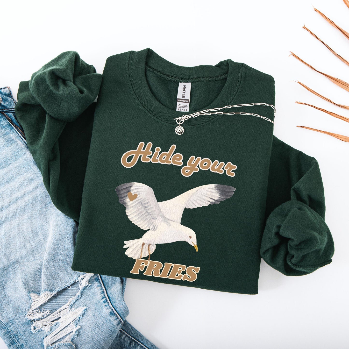 Flatlay view of a forest green colored sweatshirt with a Seagull hide your fries shirt design