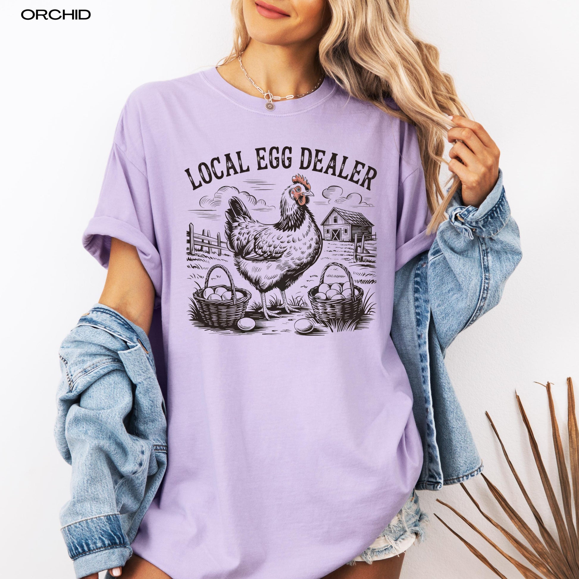 Local egg dealer comfort colors 1717 orchid t-shirt on a woman&#39;s body with a denim jacket.